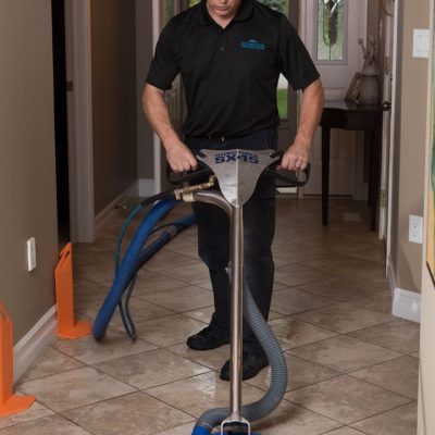 Man using a Hydro Force tile cleaning machine in a hallway.