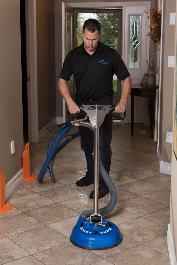 Man using a Hydro Force tile cleaning machine in a hallway.