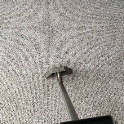 Metallic carpet cleaning tool on a light grey textured carpet.