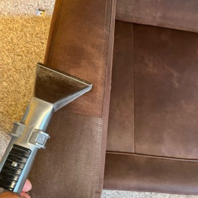 Brown upholstered furniture armrest being cleaned with an upholstery cleaner, showing a clear difference between cleaned and uncleaned areas.