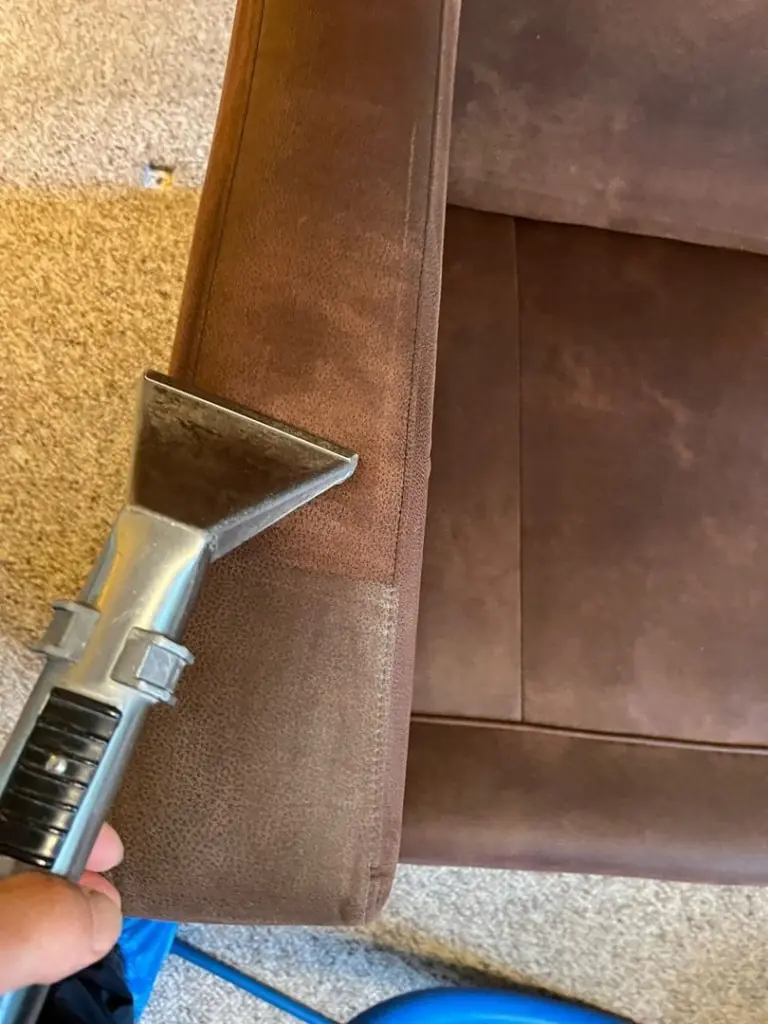 Brown upholstered furniture armrest being cleaned with an upholstery cleaner, showing a clear difference between cleaned and uncleaned areas.